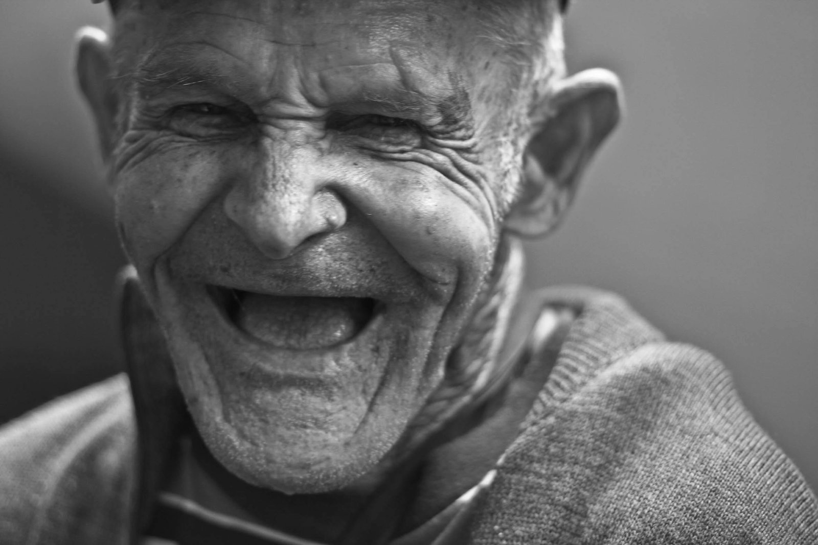 Close-up portrait of an elderly man laughing, capturing a joyful and emotive expression.