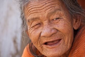 A heartwarming close-up portrait of a smiling elderly woman with deep wrinkles and joyful expression.