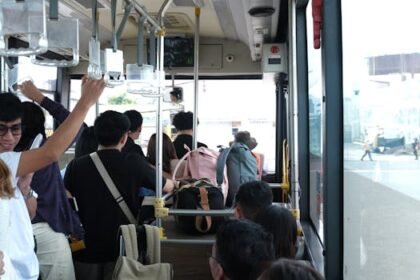 Passengers on a bus ride, holding onto rails and carrying backpacks, showcasing urban transportation.