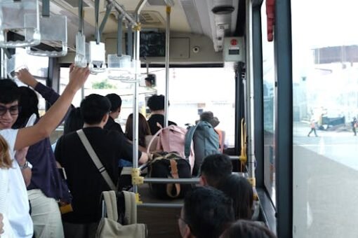 Passengers on a bus ride, holding onto rails and carrying backpacks, showcasing urban transportation.